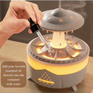 Hand adding essential oil drops into a UFO-shaped ultrasonic aroma diffuser with warm LED light and visible mist
